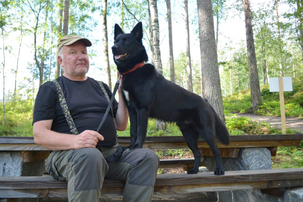 Luonnnonsuojeluliiton Etelä-Savon piirin toiminnanjohtaja Timo Luostarinen ja hänen koiransa australiankelpie Manu Mikkelin asuntomessualueella nuotiopaikalla.
