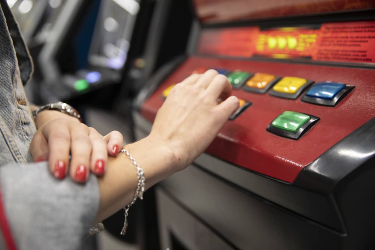nuoren naisen käsi peliautomaatilla