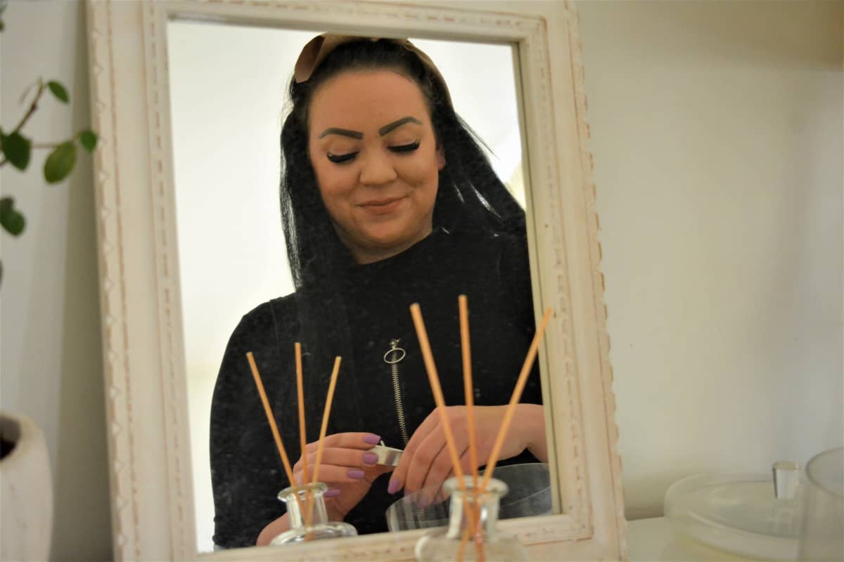 Nuori nainen Ina Virtanen sytyttää peilin edessä kynttilöitä.