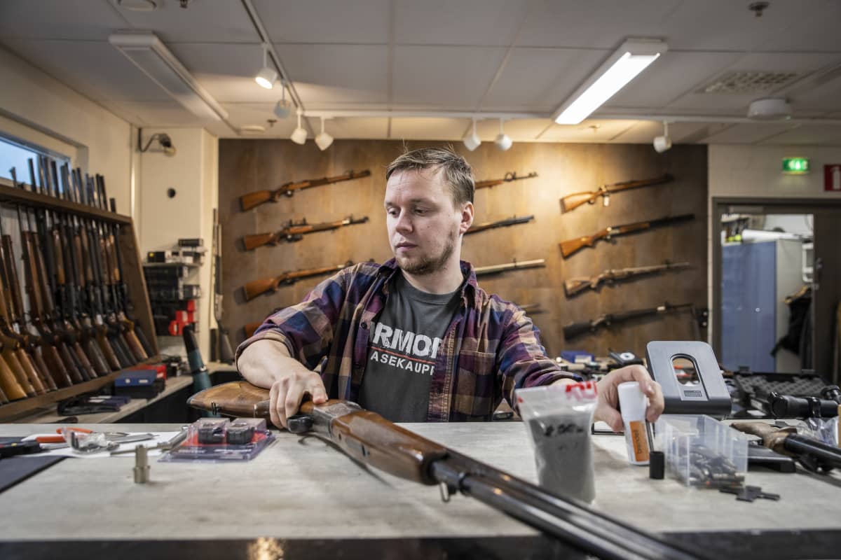 Armoria ase-liikkeen yrittäjä Veli-Matti Iskanius käsittelee haulikkoa liikkeen pöydällä.