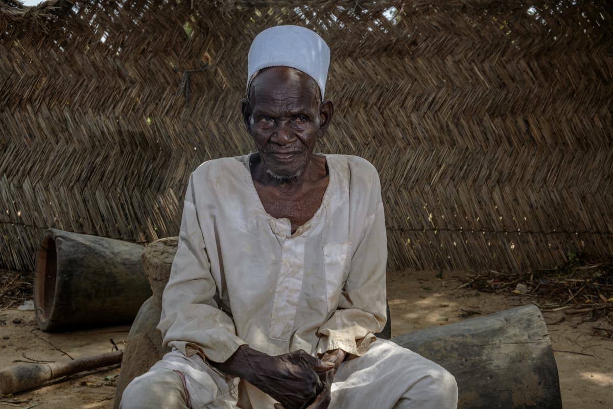 Vanha mies istuu nigeriläiskylässä.