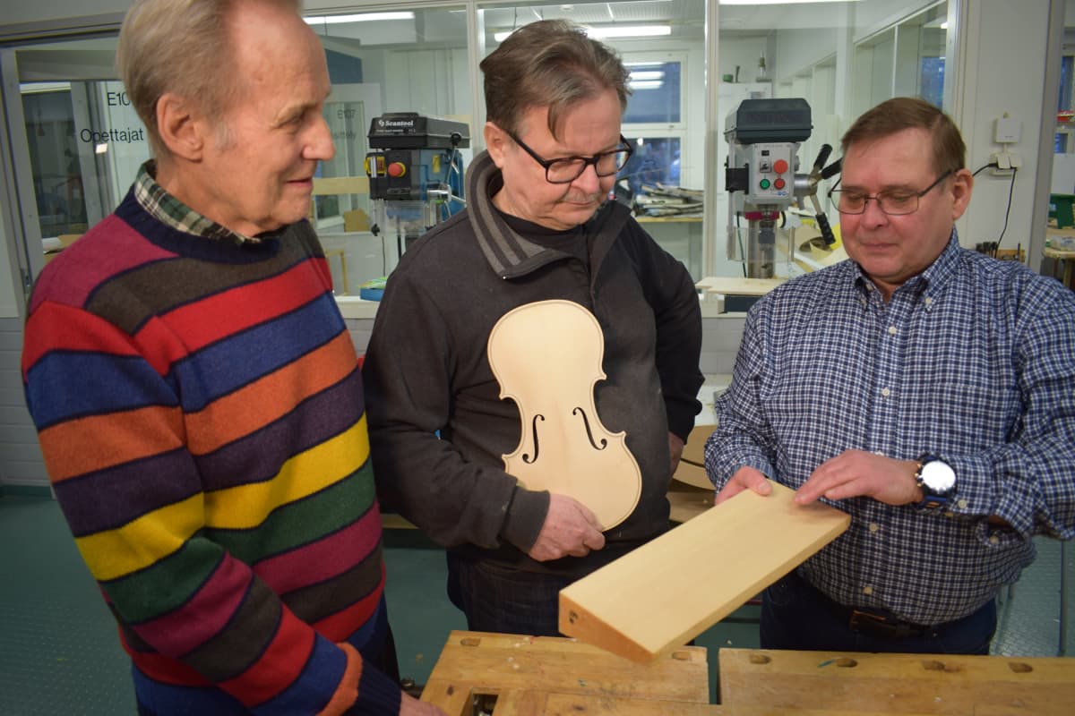 Turun työväenopiston puutyöpajassa kolme miestä suunnittelee viuluntekoa.