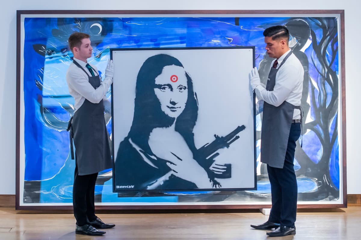 Kaksi miestä pitelee Banksyn Mona Lisa -teosta.