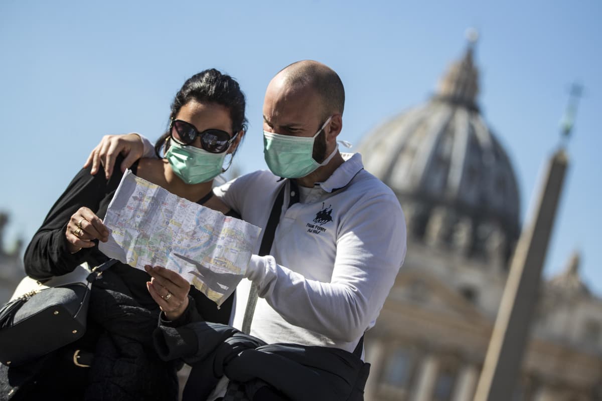 Två personer i munskydd står och tittar på en karta i Italien. 