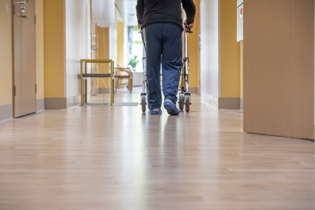 Vanhus kävelee rollaattorin kanssa kaltevaa käytävää Myyrmäen vanhustenkeskuksessa, Vantaalla.