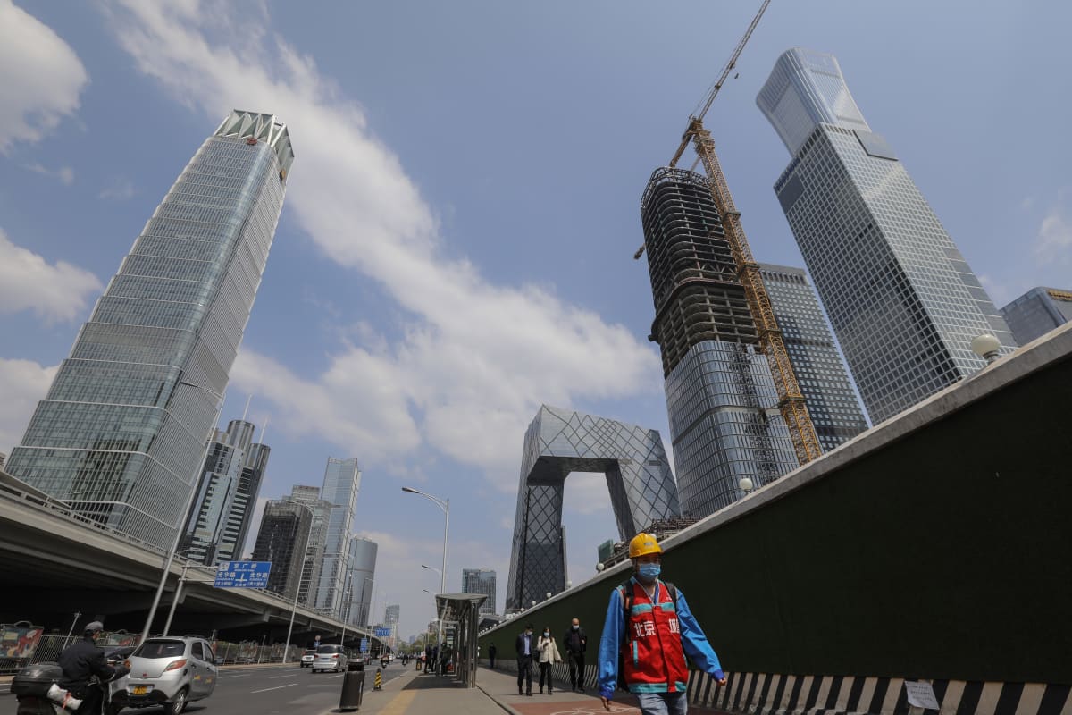 rakennusmies kävelee Pekingissä korkeiden kerrostalojen lomitse