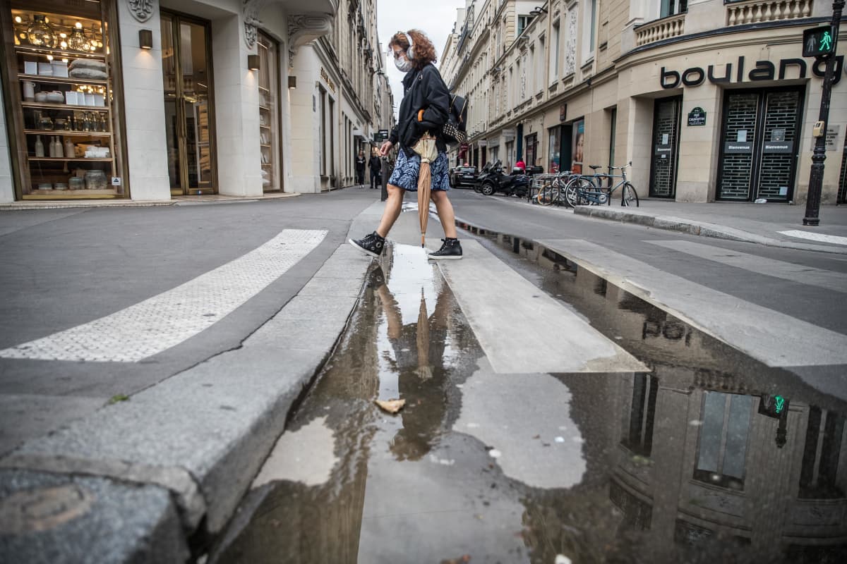 nainen ylittää suojatietä Pariisissa suojain kasvoillaan
