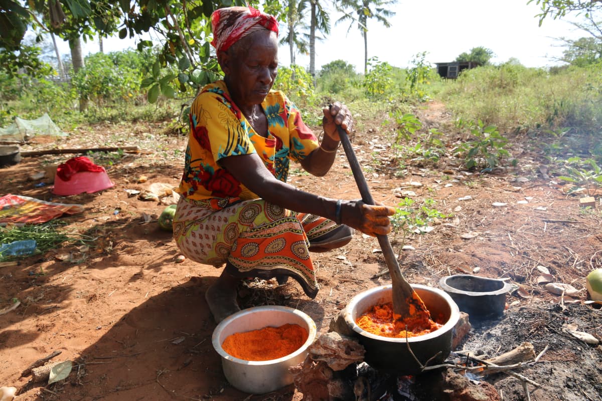 Waata-nainen valmistaa ruokaa padassa.