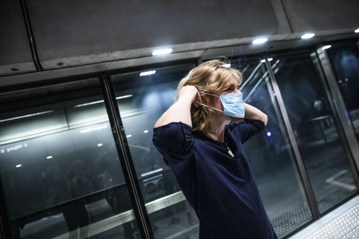 Nainen pukee kasvomaskia Kööpenhaminen metrossa 22. elokuuta, kun maskipakko julkisessa liikenteessä astui voimaan,