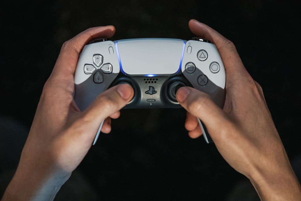 Playstation 5 pelikonsolin ohjain pelaajan käsissä.