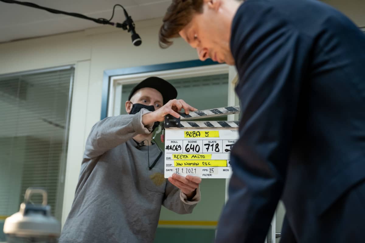 Toinen kamera-assistentti Teemu Korhonen näyttää klaffia Yellow Film & TV:n tuottaman poliisisarjan Roban kuvauksissa, oikealla näyttelijä Andrei Alén, Helsinki, 12.1.2021.