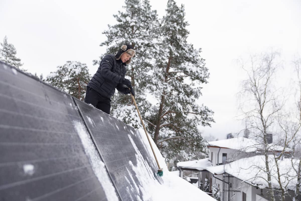 Espoolainen Ari Siipivirta pyyhkii lunta aurinkopaneelien päältä.