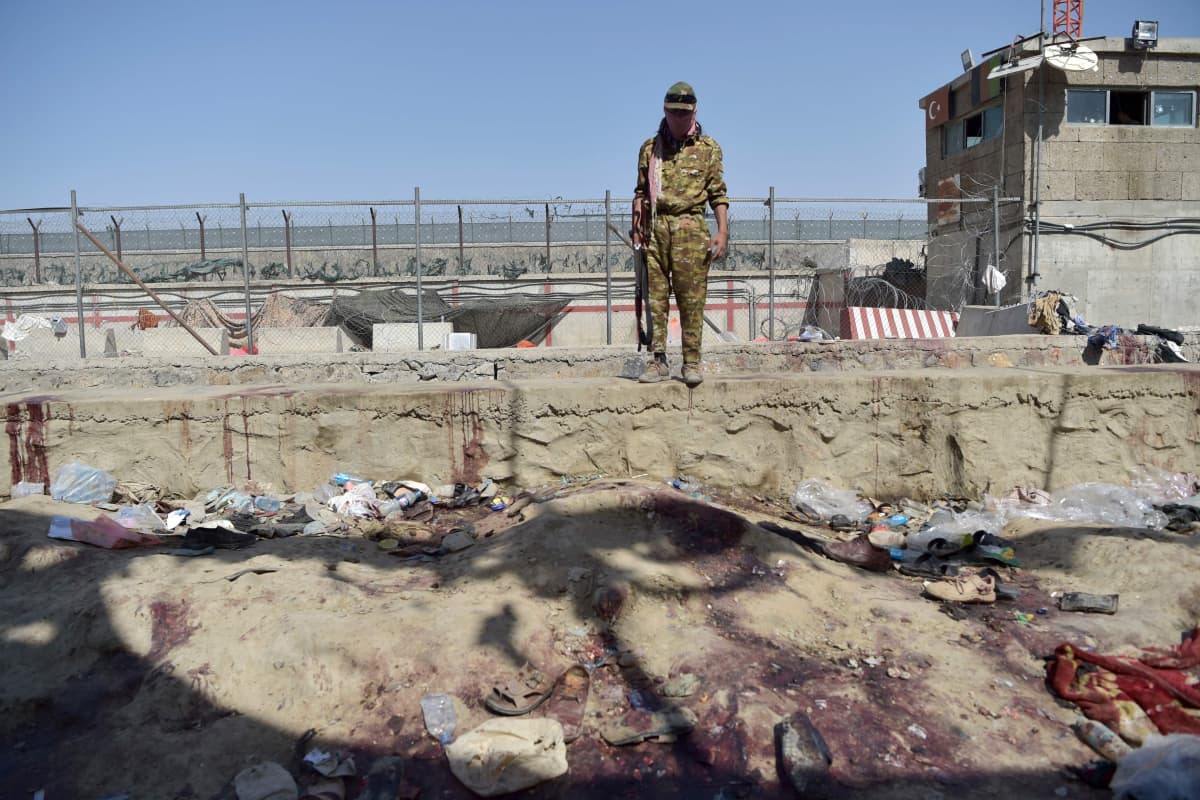 Taliban-taistelija katselee räjähdyksen jälkiä Kabulin lentoaseman lähistöllä
