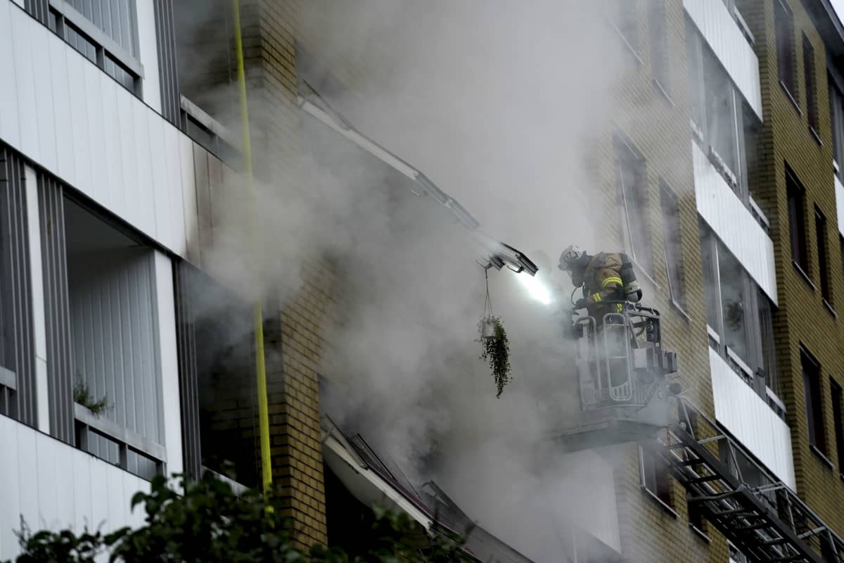 Brandman i skylift spanar in i ett brinnande hus.