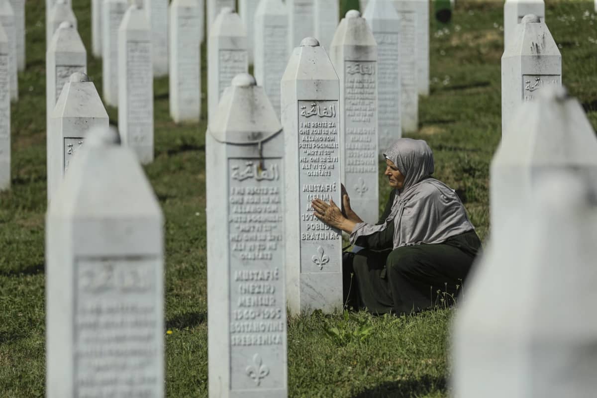 Nainen rukoilee Srebrenican kansanmurhan hautakivellä.