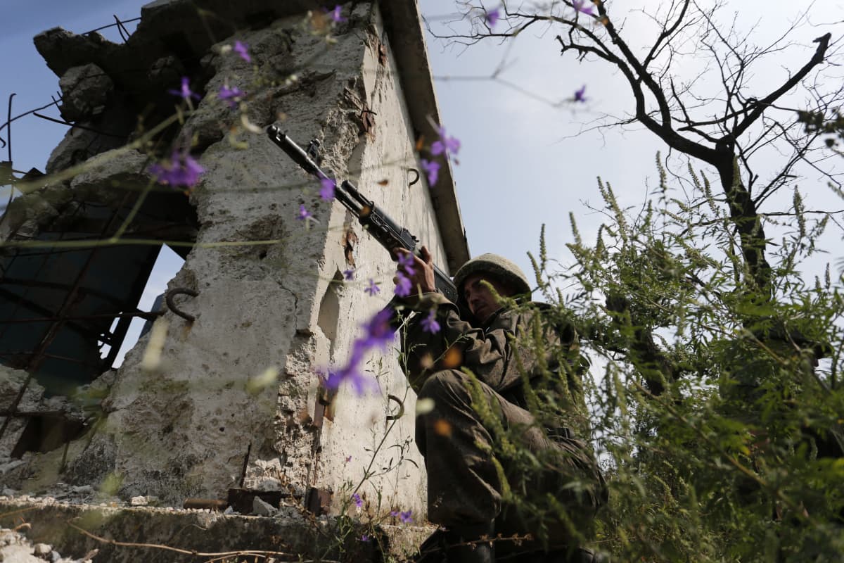 Venäläismielinen separatisti sotilas tähtää aseella.