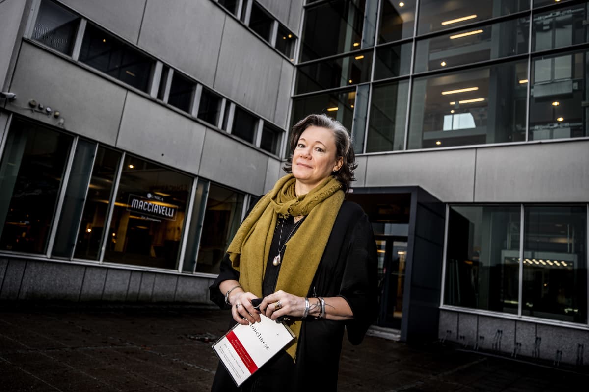 Yksinäisyystutkija Niina Junttila Turun yliopiston Educariumin edessä. Kädessä Loneliness-kirja.