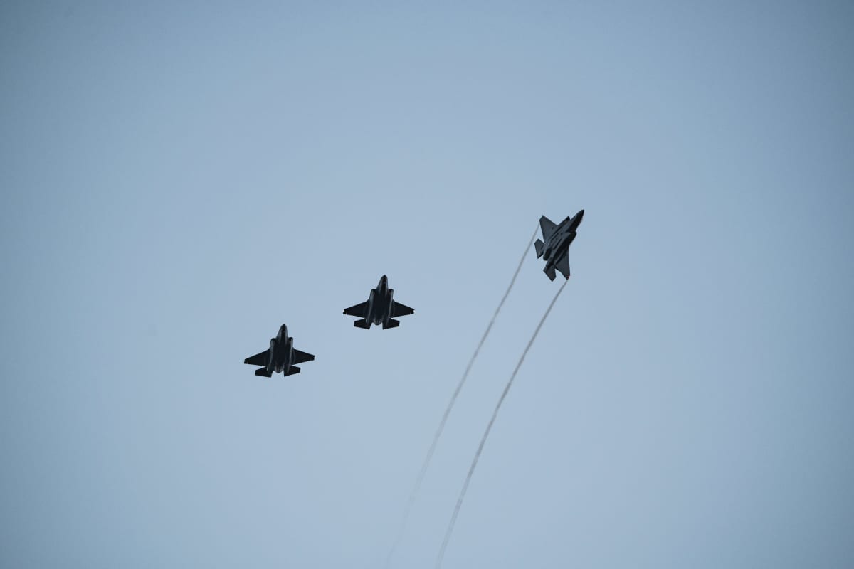 Kolme hävittäjää lentää taivaalla muodostelmassa.