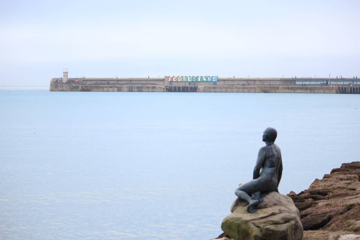 Folkstonen aallonmurtaja. Etualalla patsas joka katsoo merelle päin.