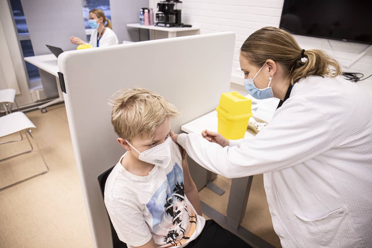 Terveydenhoitaja Johanna Saarinen antaa koronarokotteen Ukko Arposalolle.