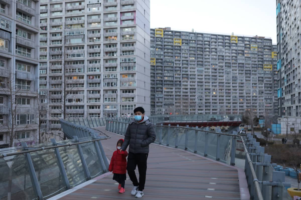 Mies ja tyttö kävelevät pekingiläisten kerrostalojen keskellä.