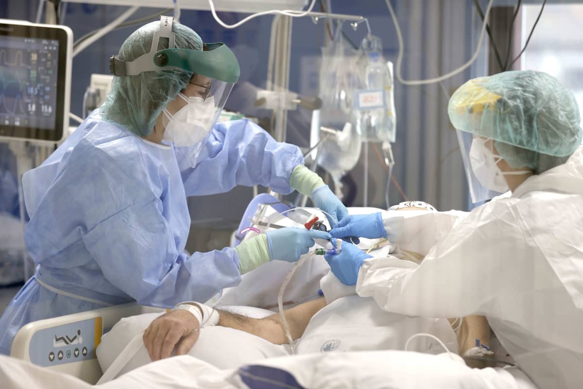Suojapukuihin varustautuneet sairaanhoitajat hoitavat koronaviruspotilasta teho-osastolla.