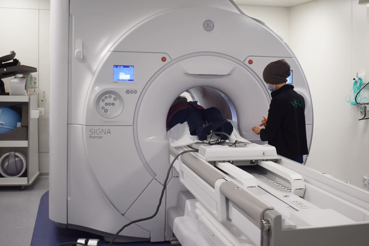 Röntgenhoitaja magneettikuvauslaitteen vieressä TYKSissä Turussa. Potilas makaa laitteen sisällä.