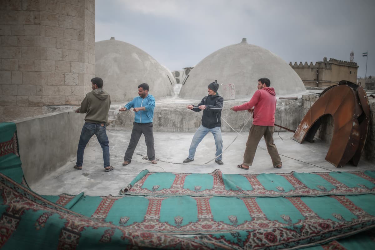 Moskeijan isojen mattojen käsittelyyn tarvittiin monta miestä ja köysiä perjantaina Idlibissä, Syyriassa.