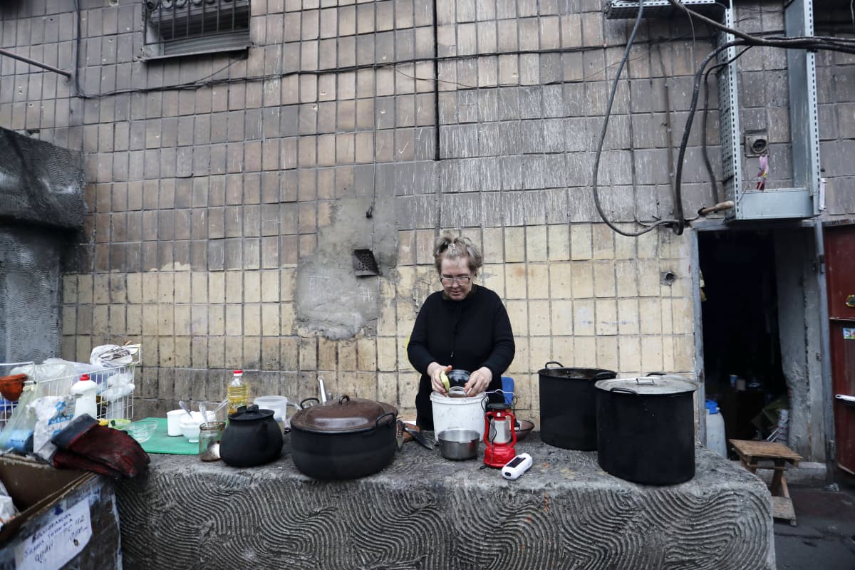 Henkilö pesee astioita ulkona.