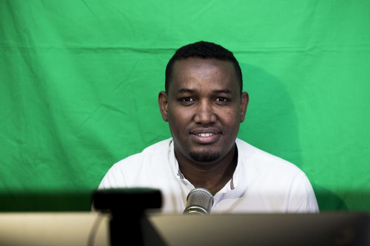 Hassan Halanen juontamassa podcast lähetystä omassa olohuoneessaan.