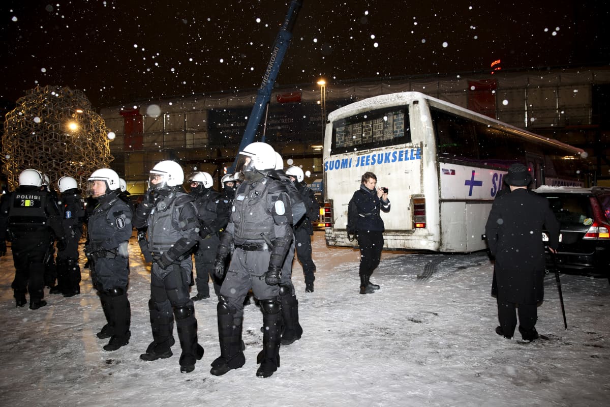 Poliisit valvovat itsenäisyyspäivän mielenosoituksia. Taustalla Suomi Jeesukselle -linja-auto.