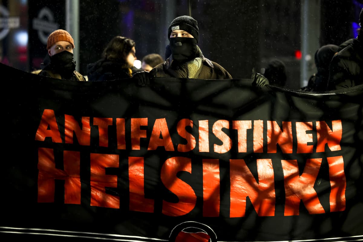 Mielenosoittajat pitelevät antifasistinen Helsinki -mielenosoituskylttiä.