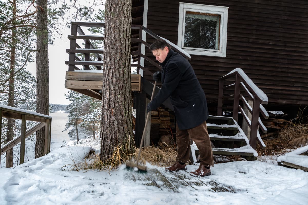 Maailman ilmatieteen järjestön pääsihteeri Petteri Taalas lakaisee lumia saunan edestä mökillään Nuuksiossa