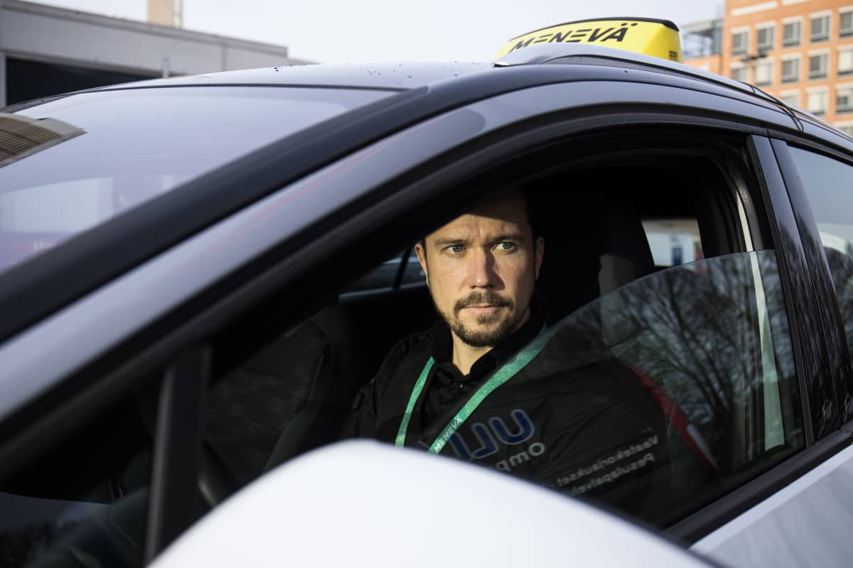 Yrittäjä Jani Viljakainen istuu sähköisessä taksiautossaan.