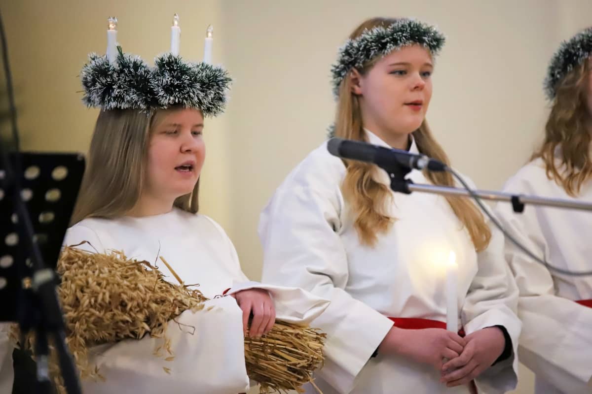Mikkelin lukion Lucia-neito 2021 Mirella Snellman laulaa Mikkelin tuomiokirkossa, vieressä Lucia-kulkueeseen kuuluva Anna Läntinen.