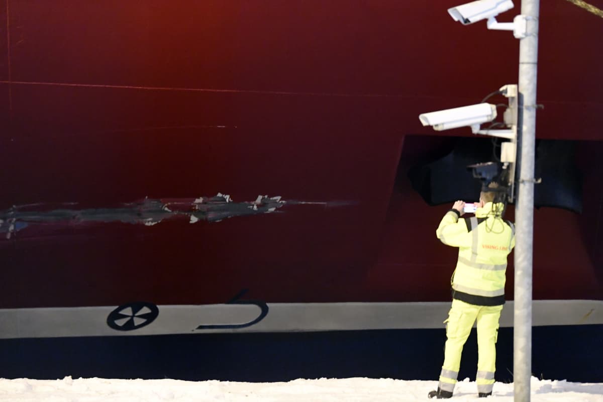 En person i neongula skyddskläder fotograferar Viking Lines kryssningsfartyg M/S Gabriella.