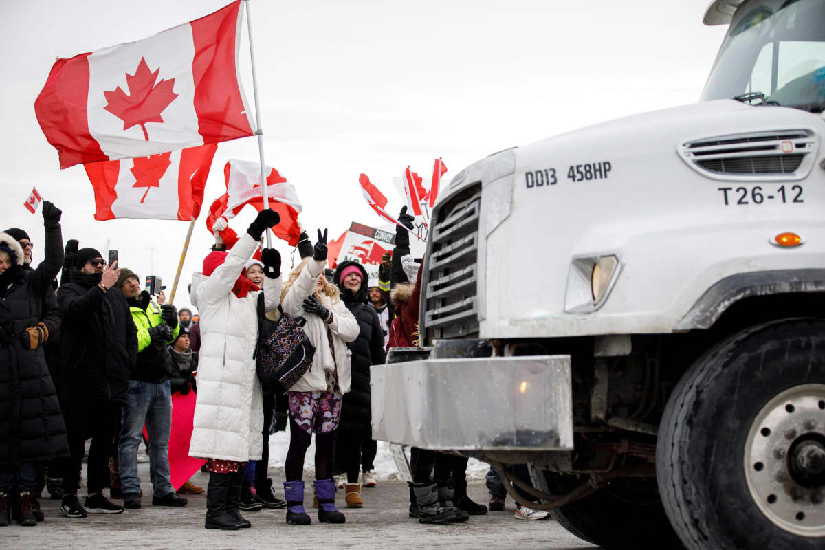 Mielenosoittajat heiluttelevat Kanadan lippua rekan vieressä.
