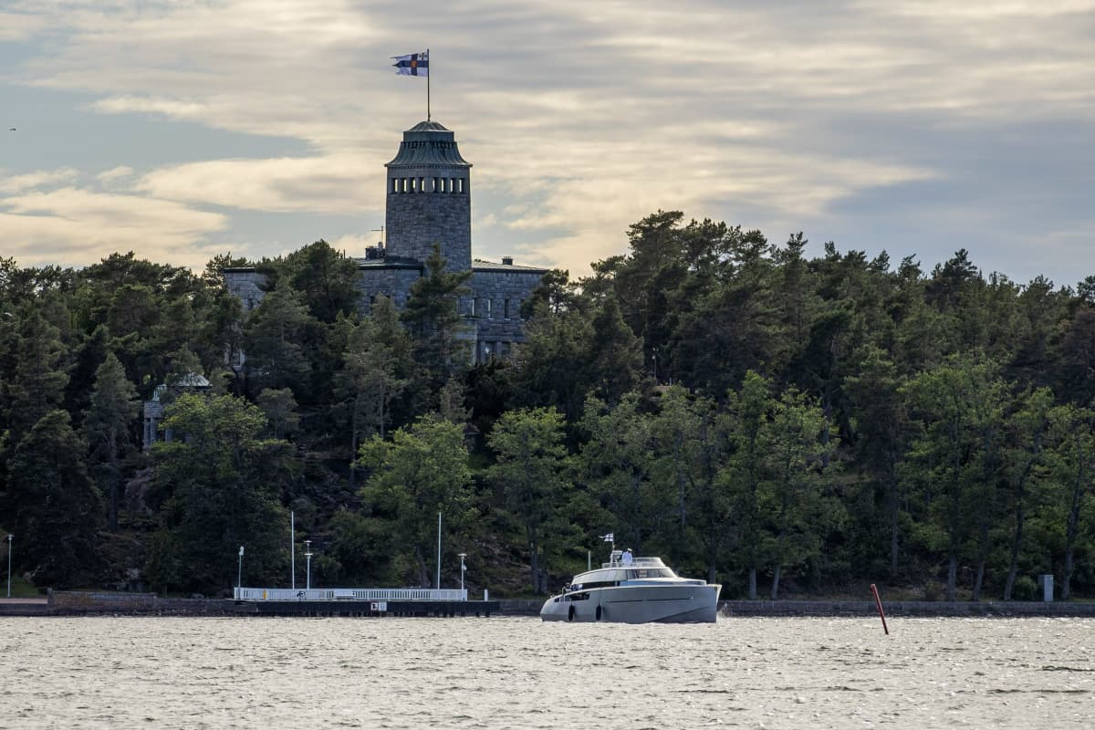 Pieni laiva Kultarannan edustalla vesillä.  Rakennuksen huipulla on Suomen lippu.