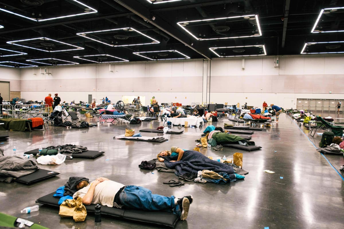 Ihmiset makaavat konferenssikeskuksen lattialla.