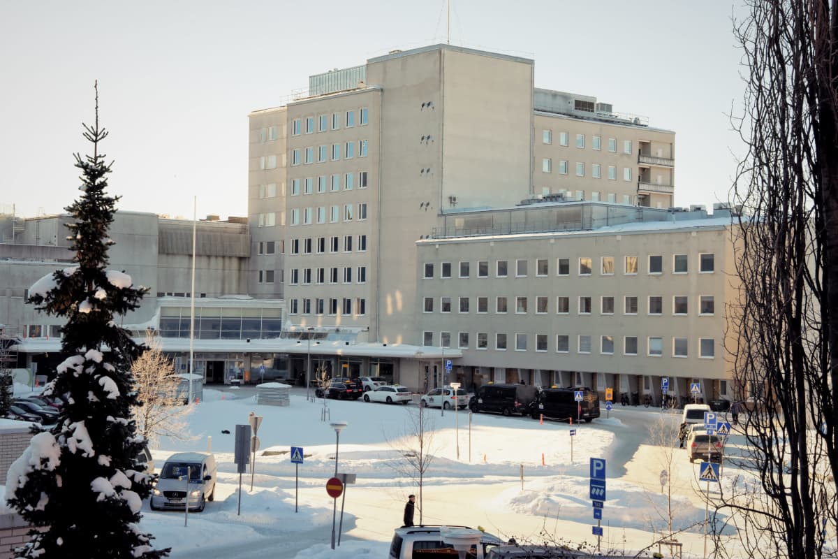 Vaasan keskussairaalan päärakennus auringonvalossa, etualalla lumen peittämiä puiden latvoja.