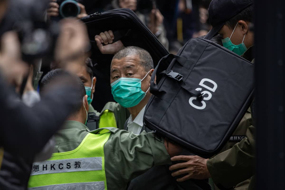 Miljonären Jimmy Lai eskorteras från häktet till domstol under hård polisbevakning.