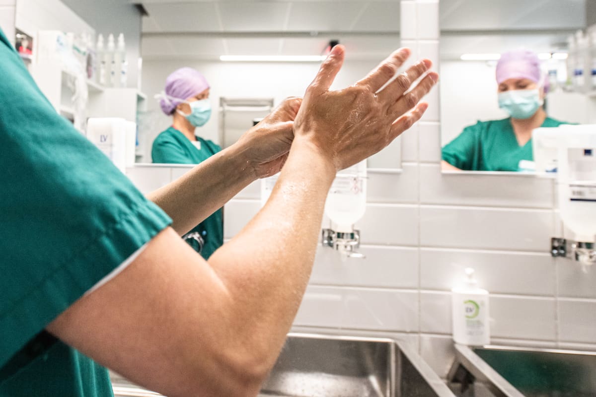 Leikkausalihoitajat pesevät käsiään ennen leikkaussaliin menoa. Kuvituskuva.