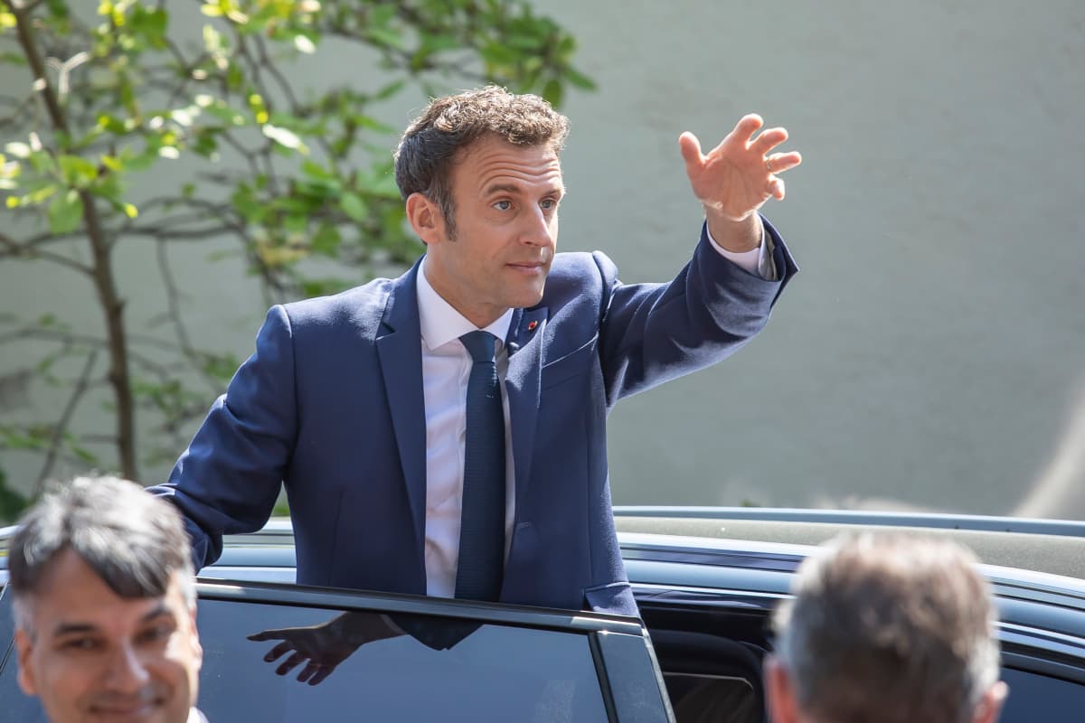 Ranskan presidentti Emmanuel Macron seisoo autossa ja vilkuttaa.