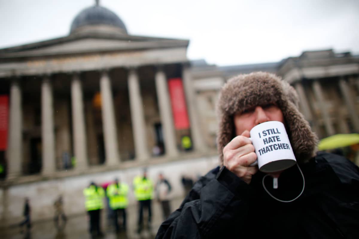 Kuva mielenosoittajasta, joka juo kupista jossa lukee "I still hate Thatcher".