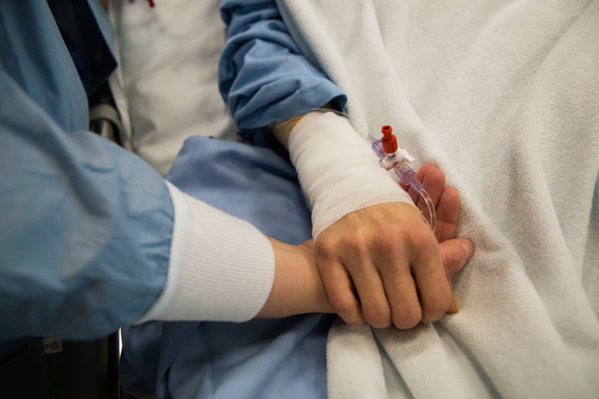 Hoitaja pitää potilasta kädestä.