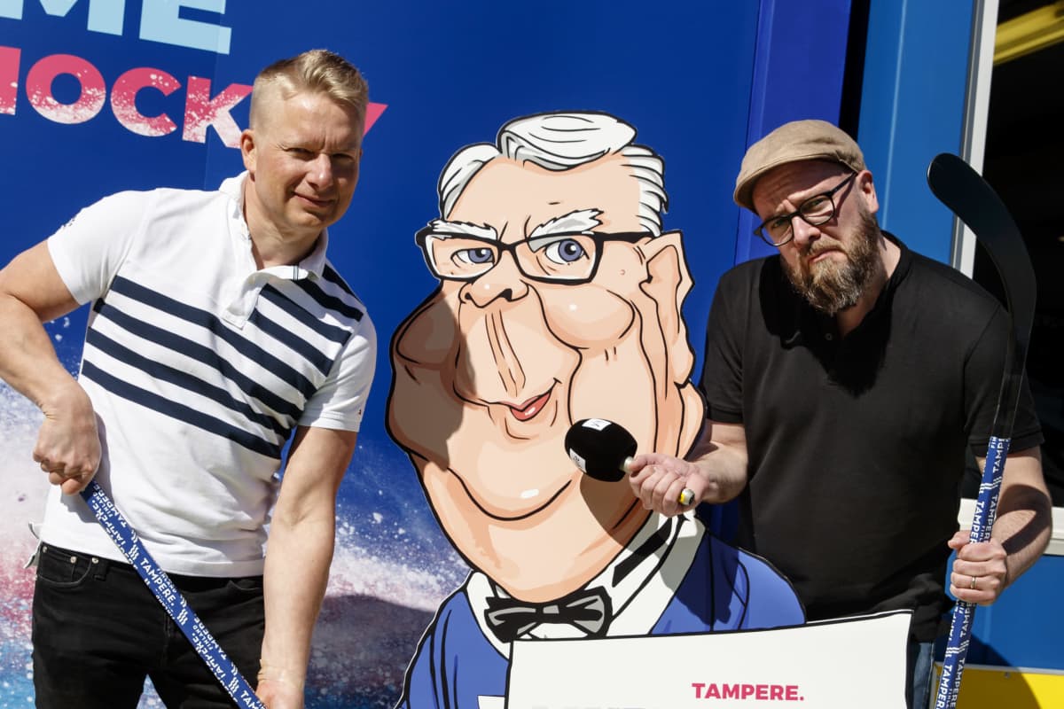 Ylen asiantuntija Juha Juujärvi ja toimittaja Jussi Paasi poseeraavat Kalervo Kummolaa esittävän kuvan vieressä.