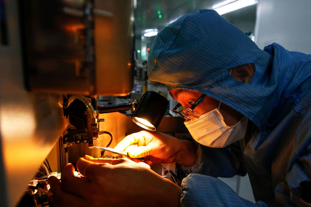 Työntekijä käyttää suojamaskia valmistaessaan mikrosirua kiinalaisella tehtaalla.