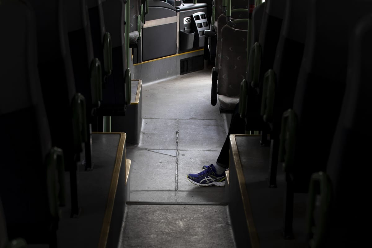 Matkustajan jalat tyhjällä bussin käytävällä.