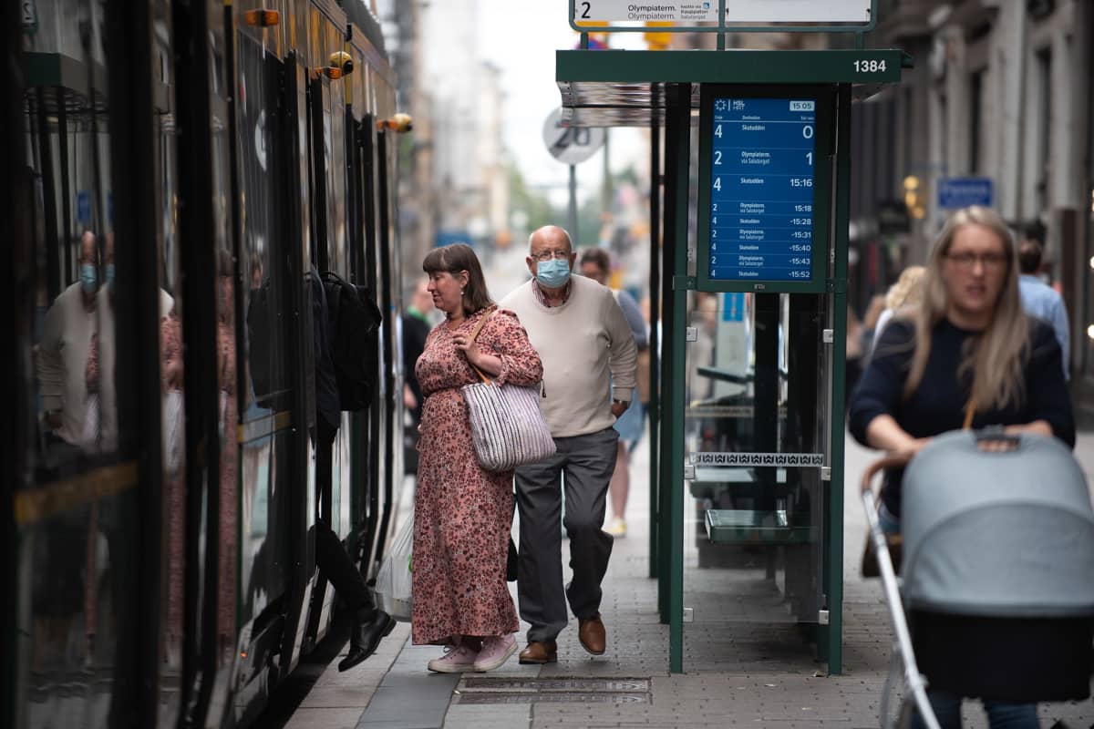 Jalankulkijoita raitiovaunupysäkillä Helsingissä.