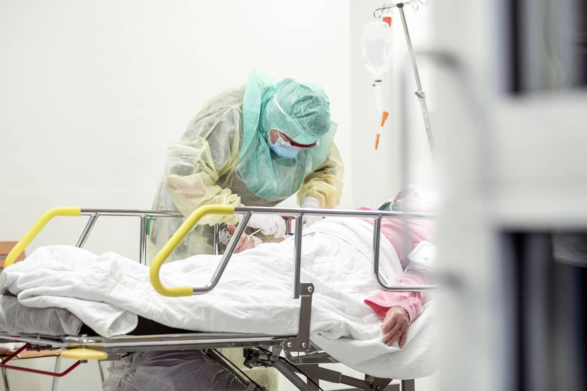 Suojavarustukseen pukeutunut hoitaja ottaa näytettä koronapotilaiden hoitoon tarkoitetulla osastolla Turun yliopistollisessa keskussairaalassa. 